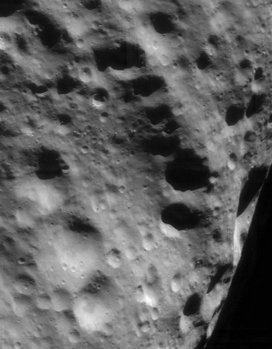 An ancient ridge on Eros trending across a densely cratered surface in raking sunlight.