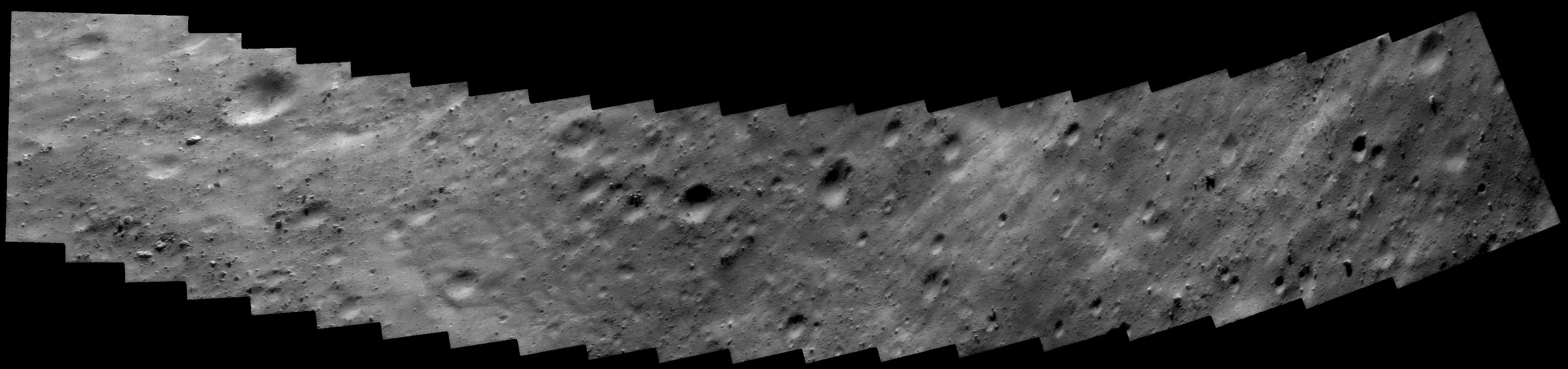 Closest-approach mosaic of asteroid 433 Eros, a long strip of cratered rock and pooled regolith in raking sunlight.