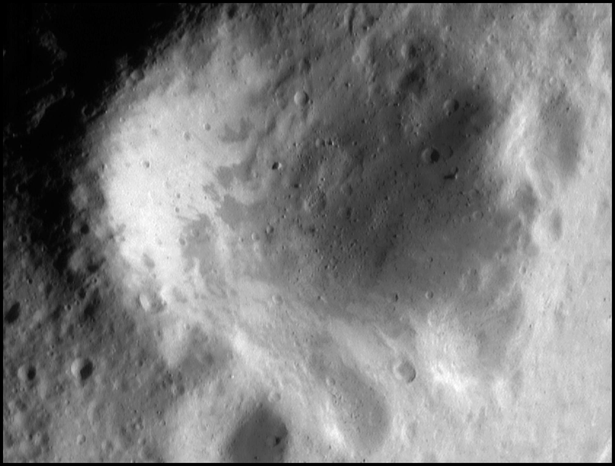 NEAR Shoemaker mosaic of the crater NASA called Psyche on 433 Eros: a raised rim in low light, smaller craters along the rim, a boulder on the wall.